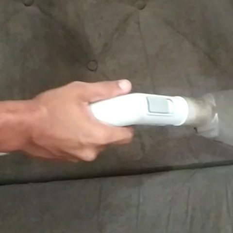 Equipamento de limpeza em uso sobre estofado